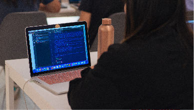 A woman in a black sweater is coding using javascript.